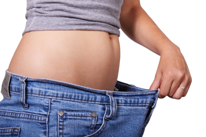 Woman waistline pulling pant waist away showing weight loss